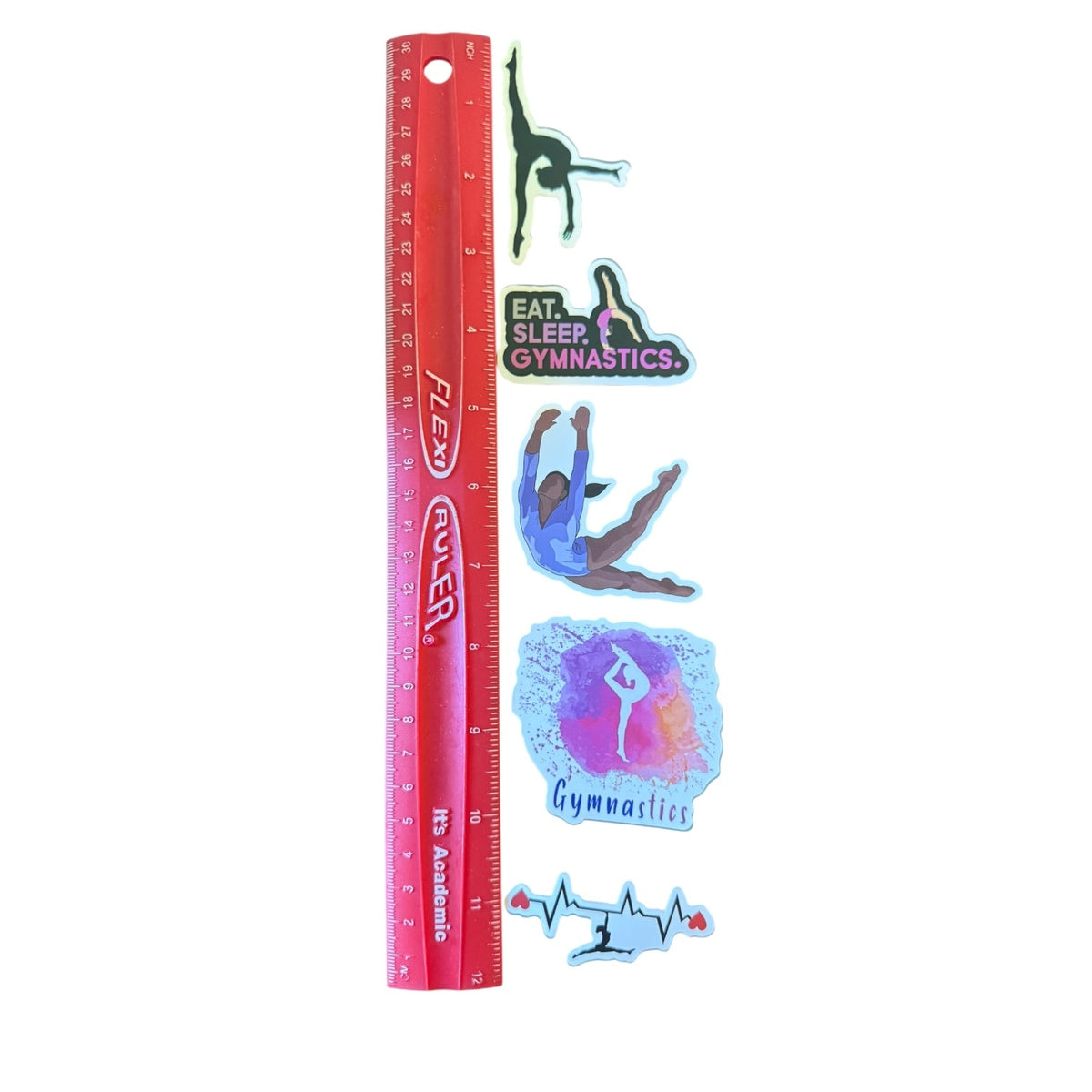 A set of gymnastics-themed stickers displayed next to a red plastic ruler on a white background. The stickers feature various gymnasts in different poses and designs, including one with the text 'EAT SLEEP GYMNASTICS' and another with a heartbeat line motif.