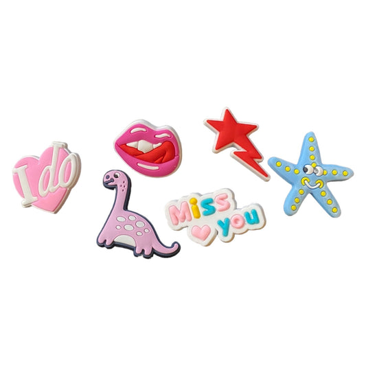 Set of colorful decorative shoe charms including 'I do', lips, star, dinosaur, and 'Miss you' on a white background.