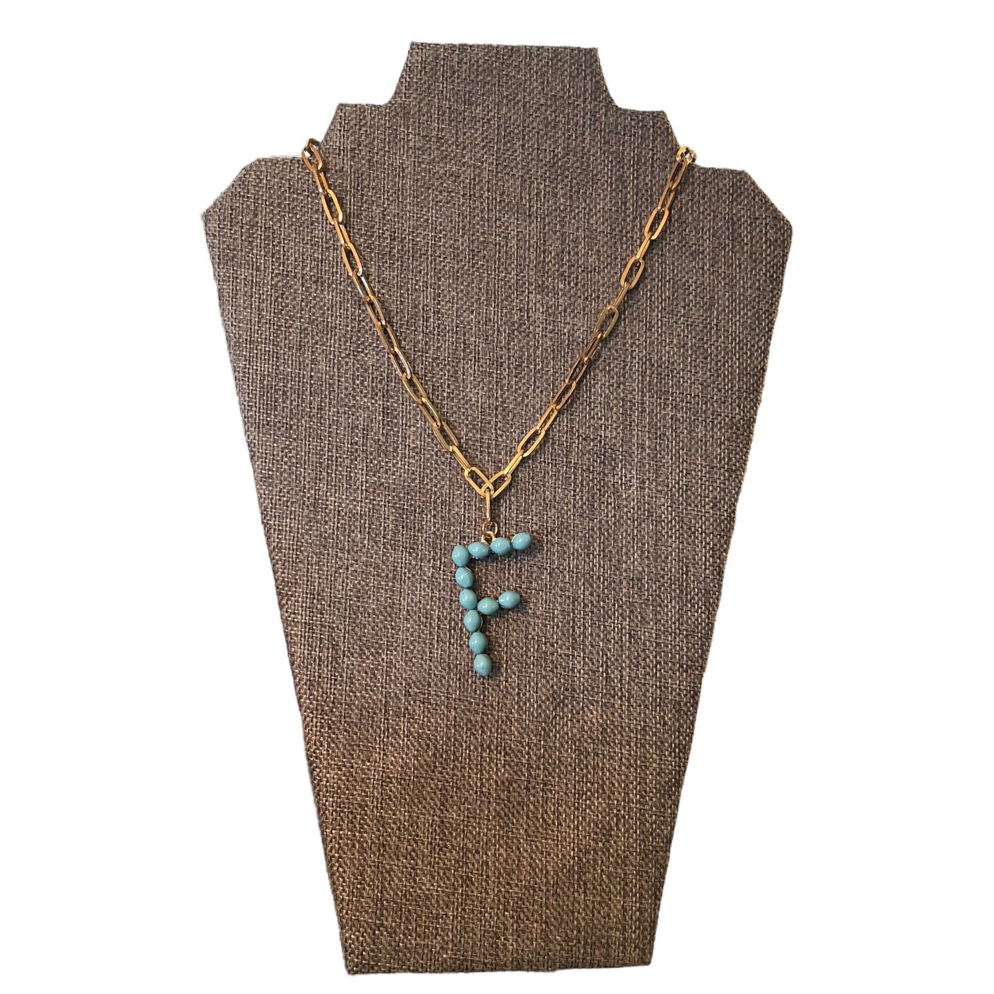 Necklace with turquoise 'F' pendant on a brown bust