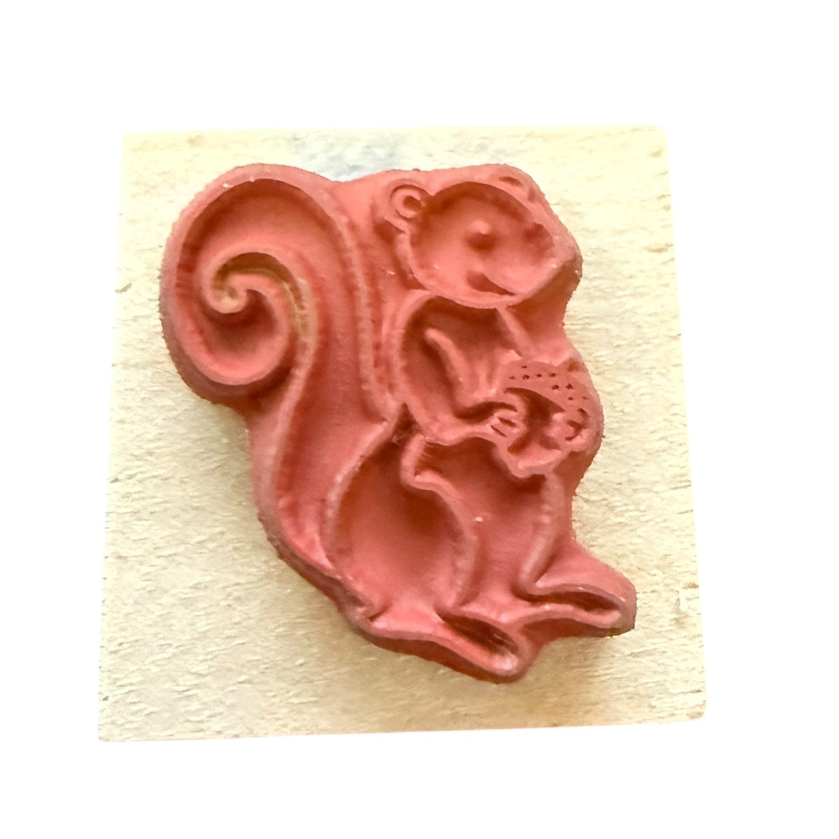 Pink squirrel-shaped stamp on a beige background