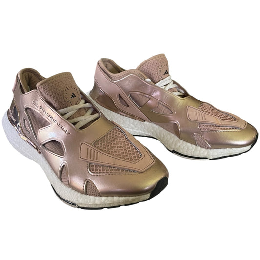 Pair of rose gold athletic shoes on a white background