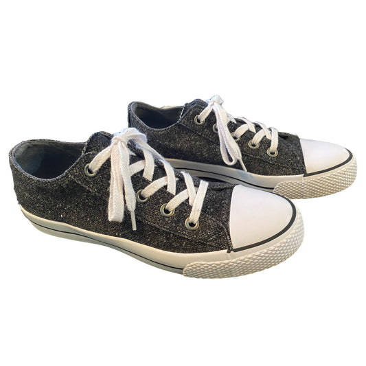 A pair of low-top canvas sneakers in a dark gray , featuring white laces, white rubber toe caps, and white midsoles with black trim.
