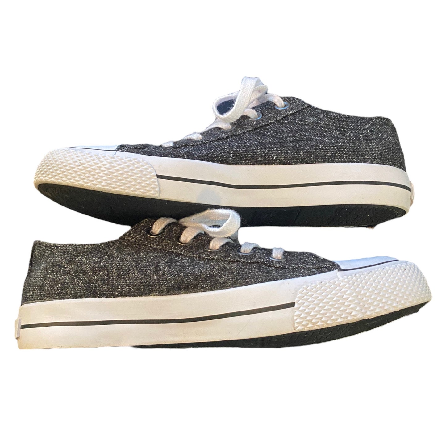 A pair of low-top canvas sneakers with a dark gray upper, white laces, and white rubber toe caps and midsoles, shown against a plain white background.