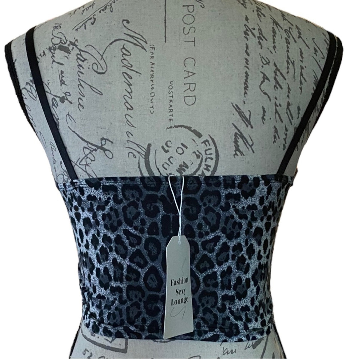 A sleeveless top displayed on a dress form, featuring a dark navy leopard print pattern across the bodice and thin black shoulder straps. The dress form has a vintage-style gray script print.