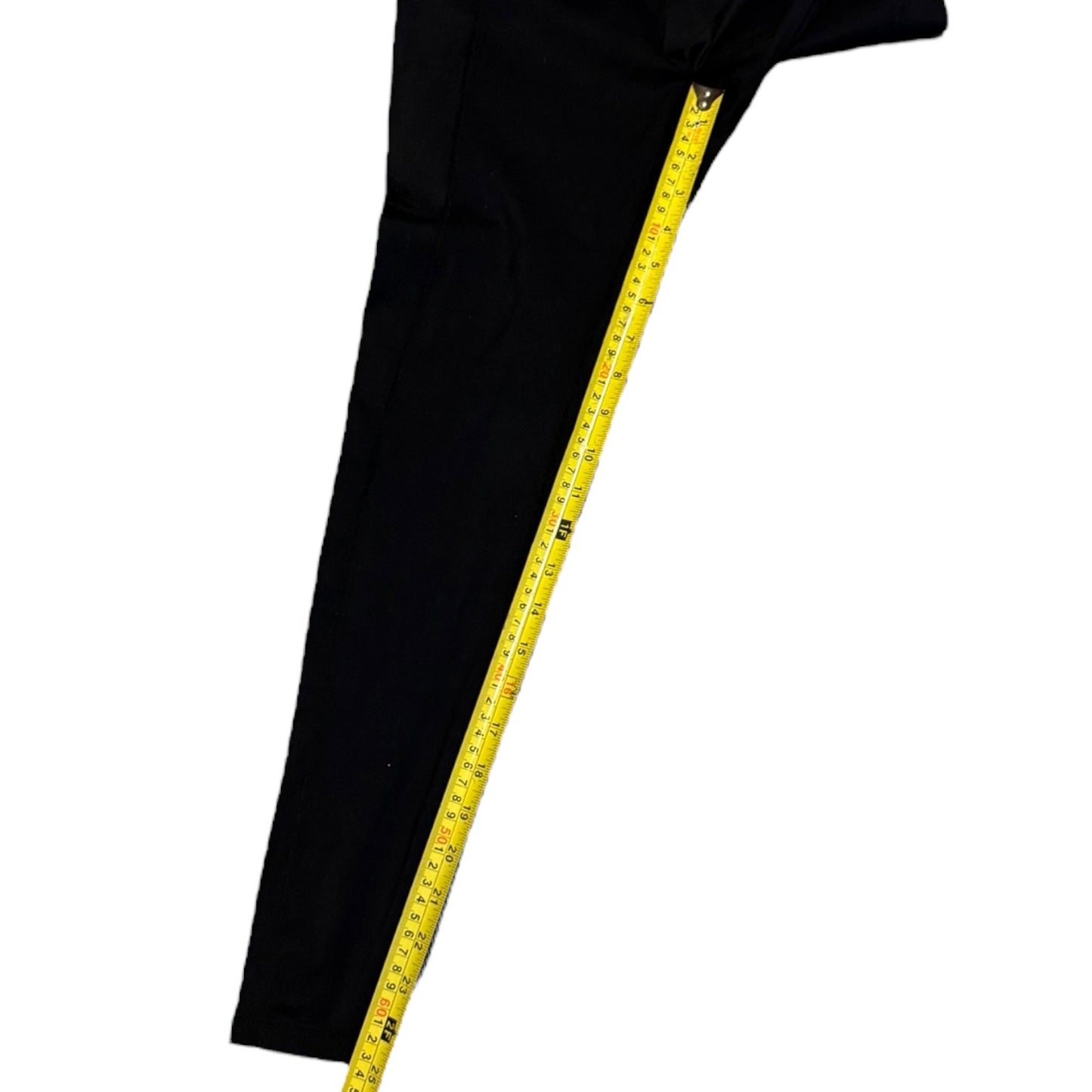 Inseam on black leggings with a yellow measuring tape draped over it on a white background
