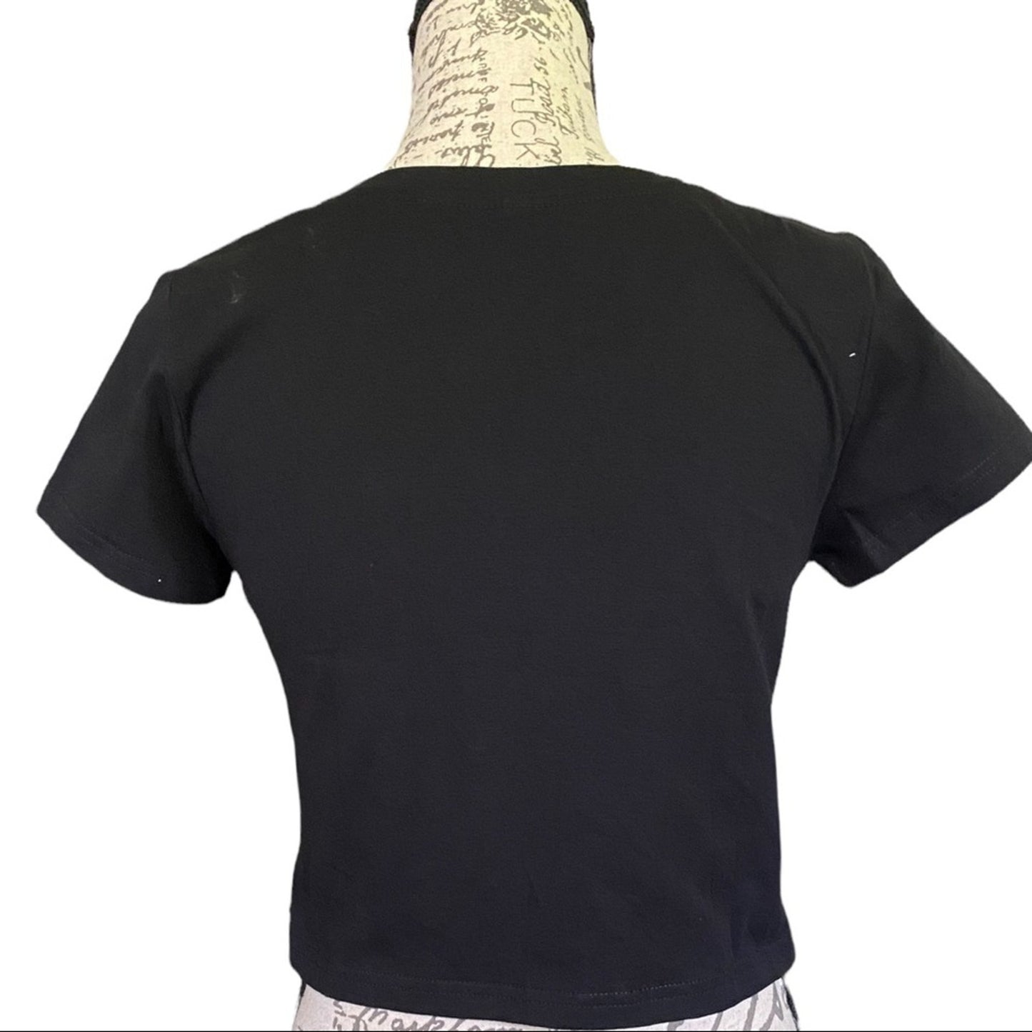 A black short-sleeve crop top shown from the back on a mannequin torso against a plain white background.