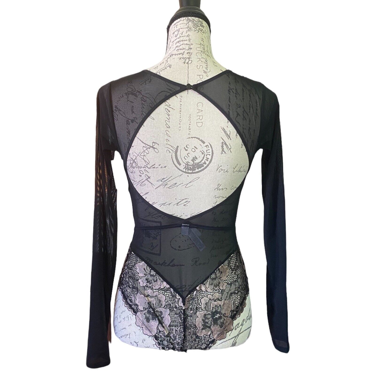 A long-sleeve black mesh and lace bodysuit displayed on a dress form mannequin against a white background.