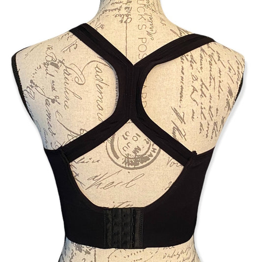 Back of black sports bra on a mannequin with a vintage-style script background