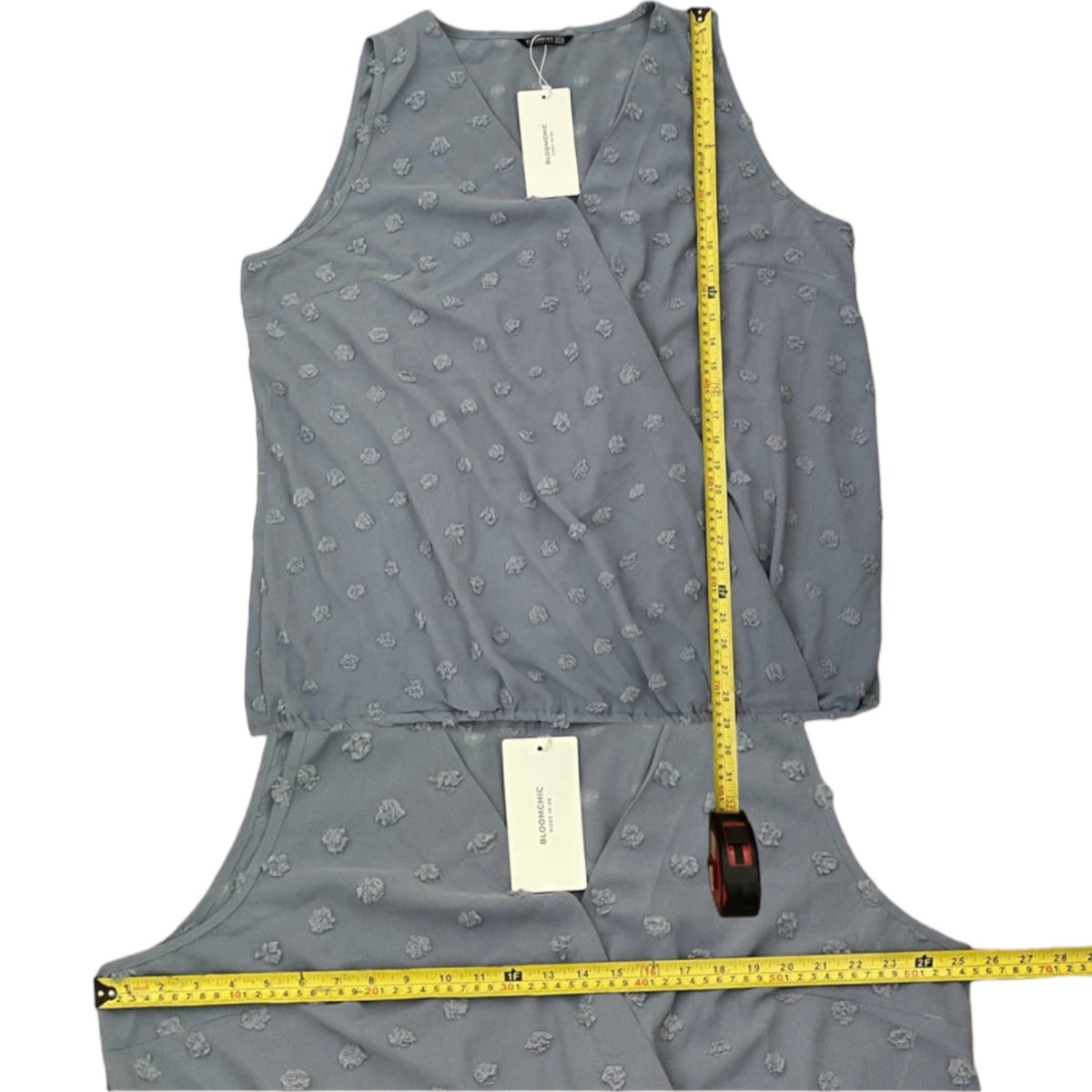 Blue sleeveless top with a measuring tape on a white background
