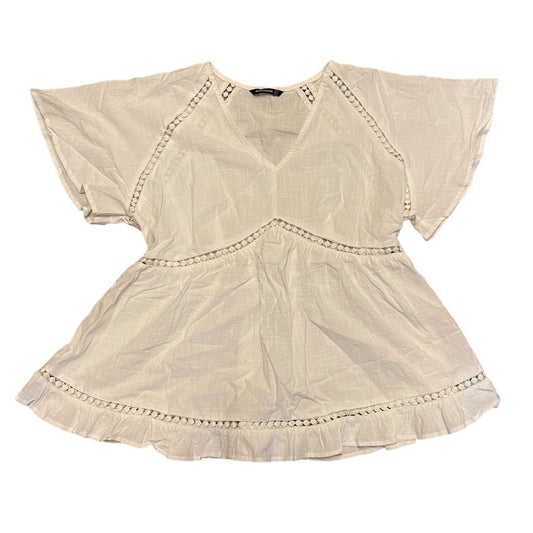 White shirt laying flat with short sleeves on a white background