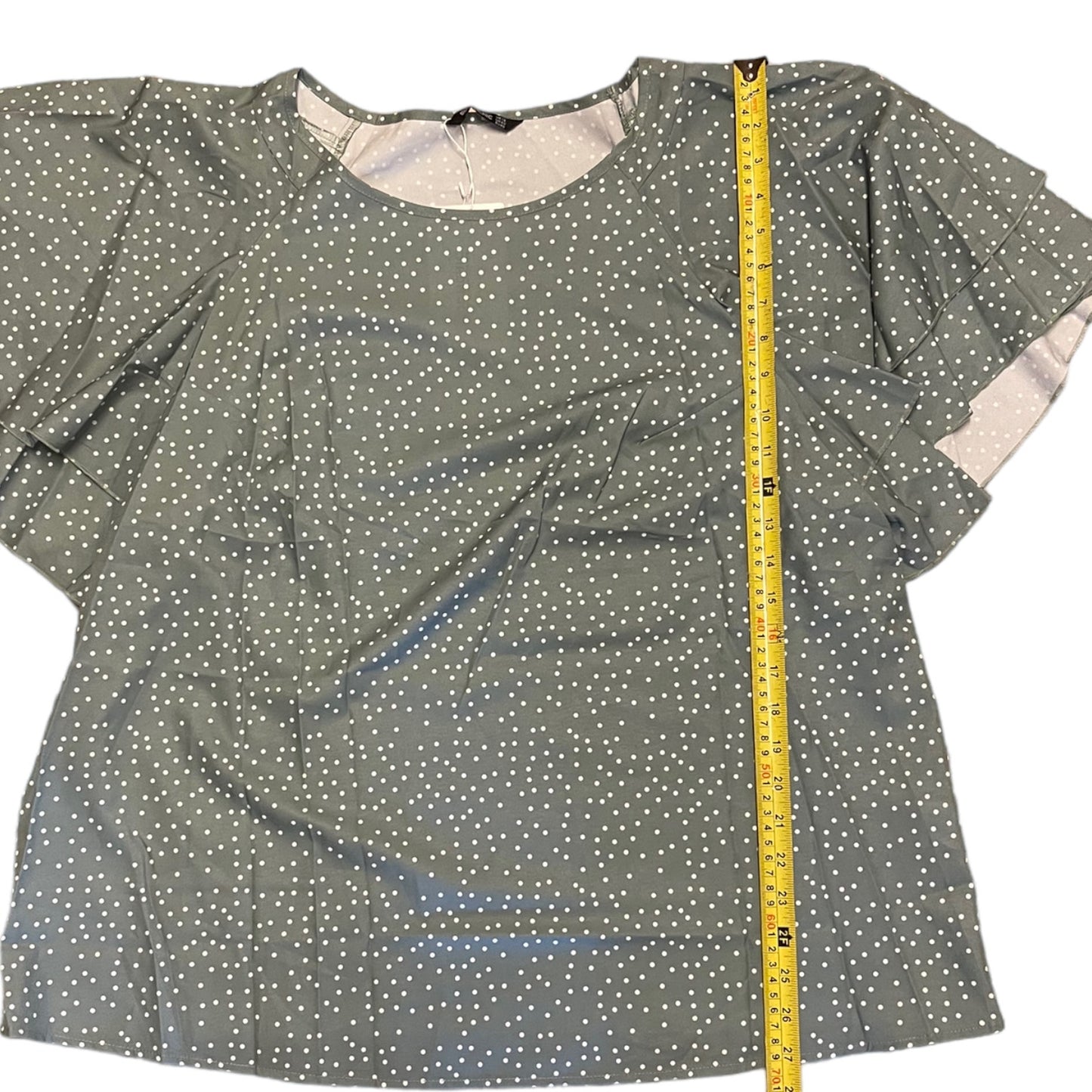 Green polka dot blouse with a measuring tape on a white background