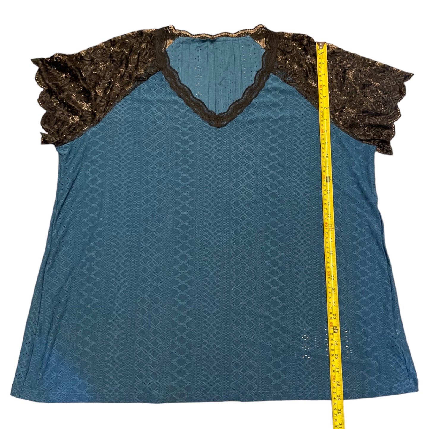 Blue textured top with black lace trim and a measuring tape on a white background