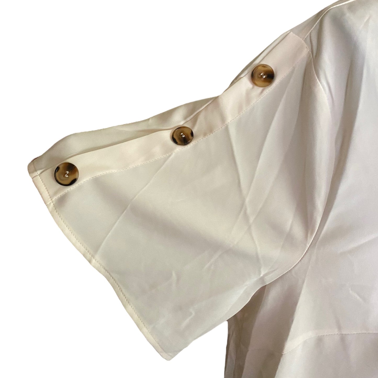 Close-up of a off-white blouse sleeve with three brown buttons along the cuff, shown against a plain white background.