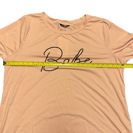 A short-sleeve t-shirt with a black cursive 'Babe' graphic across the chest, shown with a yellow tape measure stretched horizontally across the chest to indicate size.