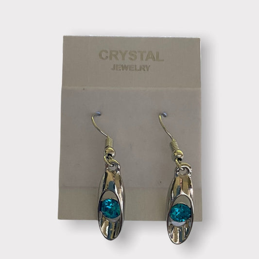 A pair of dangling earrings with silver-toned metal frames and round blue- crystal centers, displayed on a jewelry card labeled 'CRYSTAL JEWELRY'.