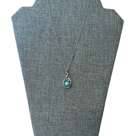 A silver teardrop pendant necklace with a faux blue pearl, displayed on a gray fabric jewelry bust against a white background.