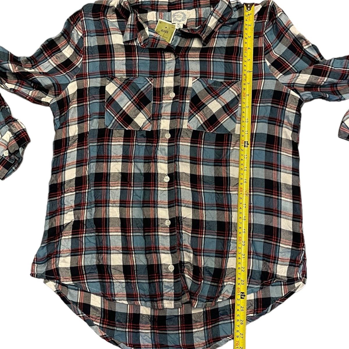 A long-sleeve plaid button-up shirt laid flat on a white background, with a yellow measuring tape running vertically down the center to show the height.