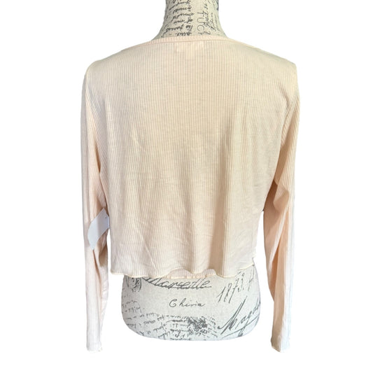 A light beige ribbed knit long-sleeve crop top shown from the back on a patterned dress form mannequin against a white background.