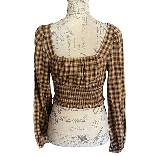 Brown plaid long-sleeve top on a mannequin with a script-patterned base.