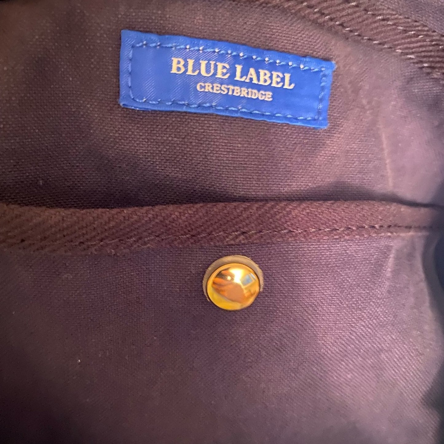 interior of bag with a blue label reading 'Blue Label Crestbridge' and a gold button.