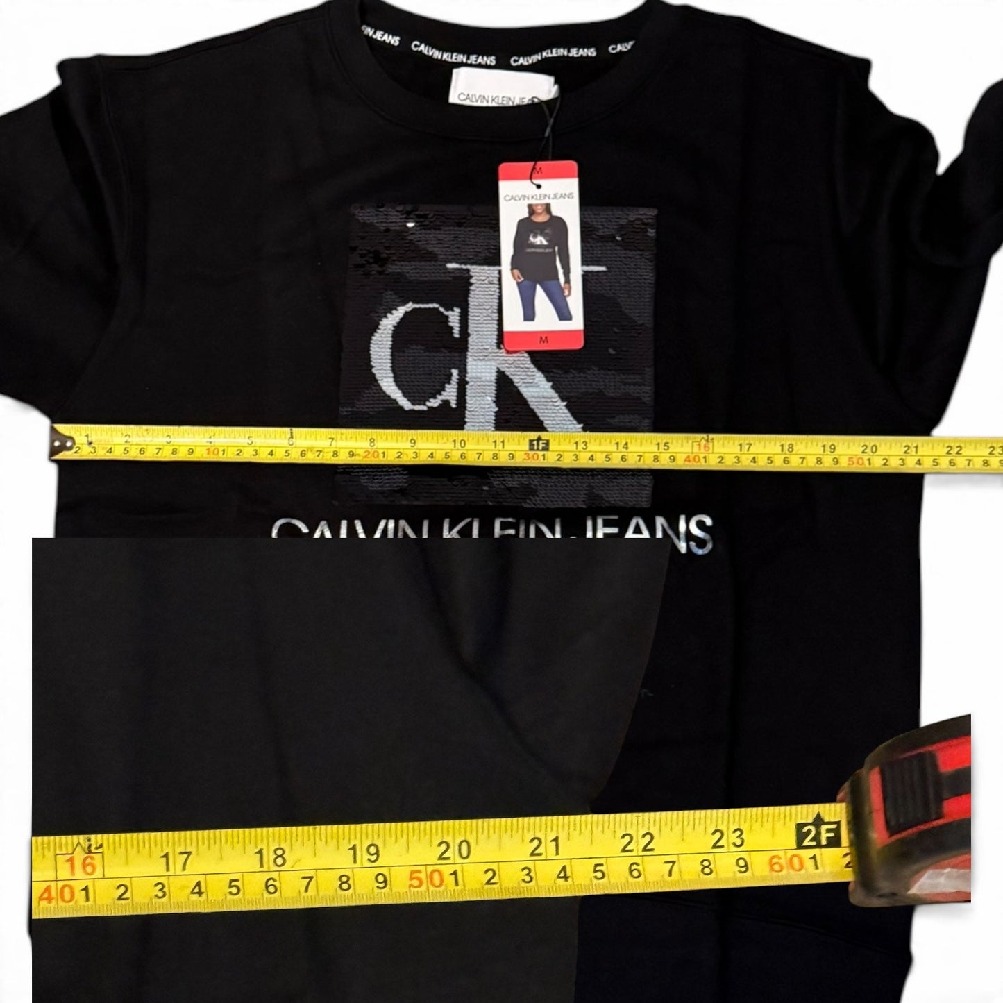 Black Calvin Klein shirt with a measuring tape and brand tag on a white background