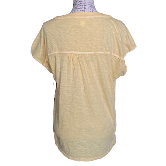 A pale yellow short-sleeve top displayed on a mannequin from the back, featuring a gathered waist seam and a relaxed, loose fit.