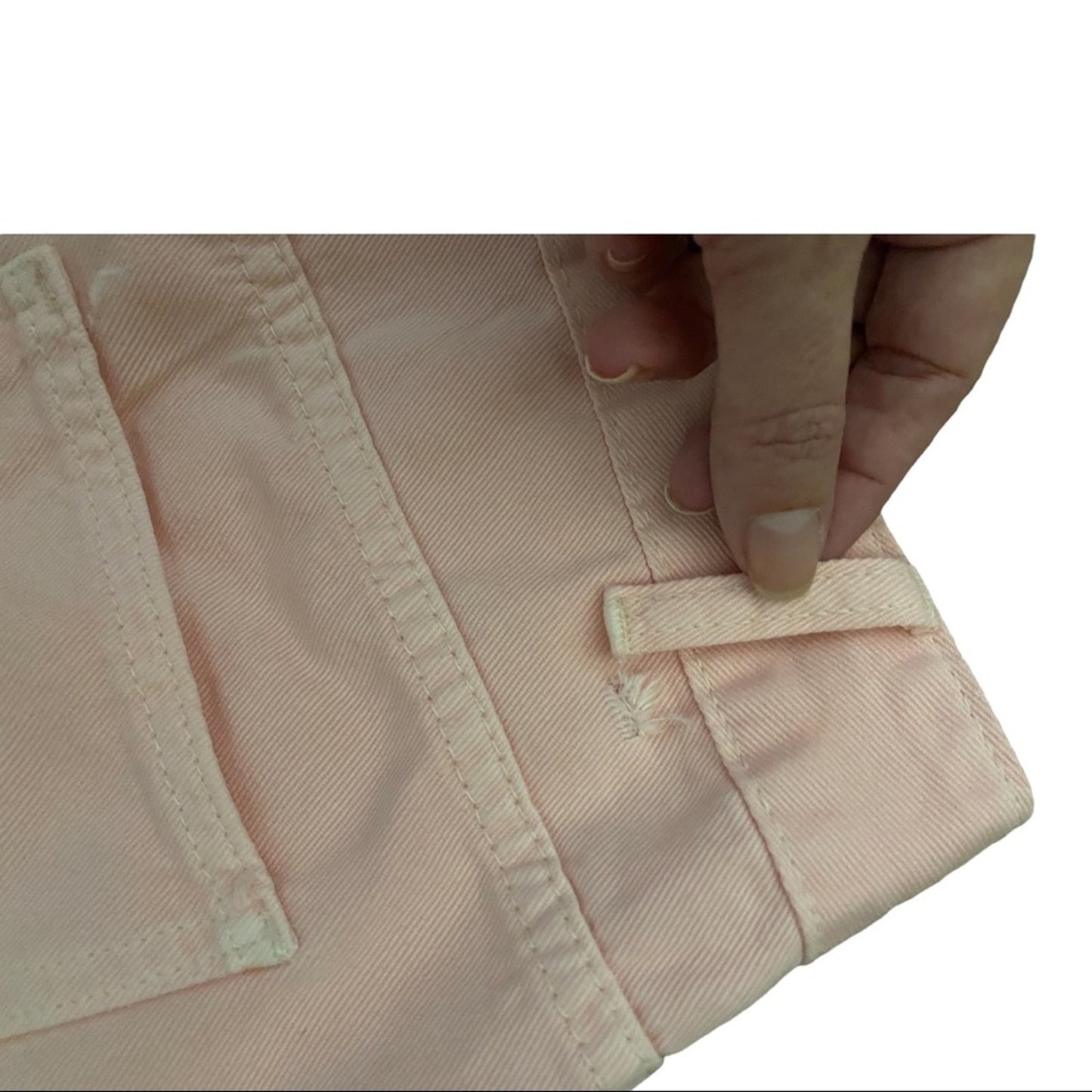 A close-up of pink pants showing a hand showing a damaged loop from the side.