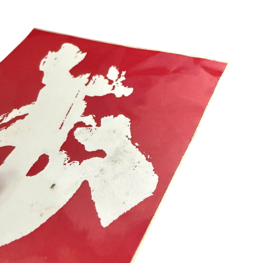 Red sticker with white abstract design on a white background showing issues on corner