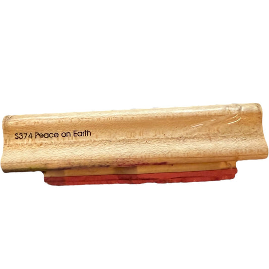 A wooden stamp block with the engraved text 'S374 Peace on Earth' on a plain white background.