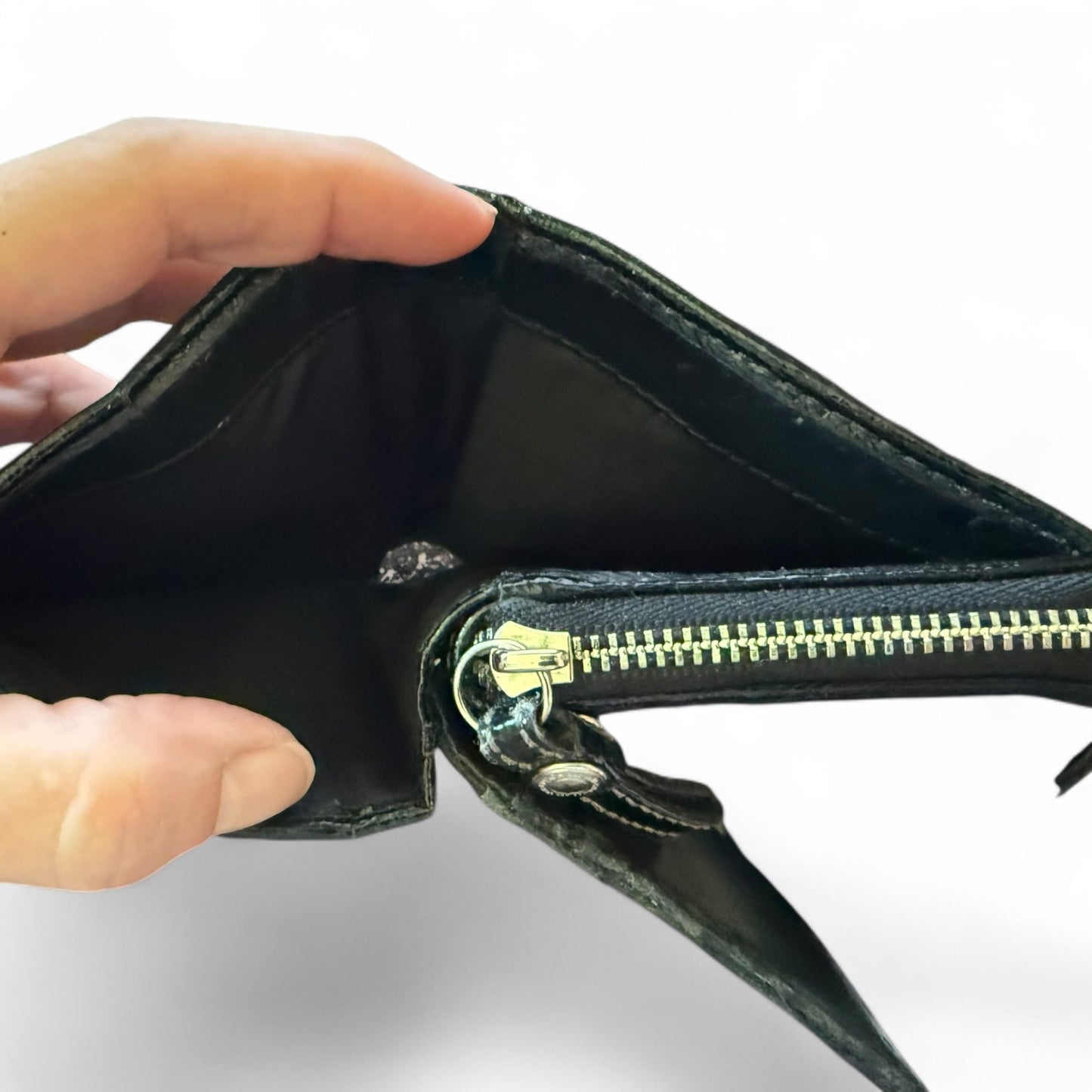 Hand holding an open black leather wallet with a gold zipper on a white background