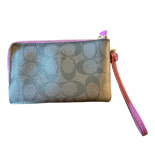A Coach wristlet pouch in signature monogram coated canvas with a pink zipper and wrist strap, shown on a plain white background.