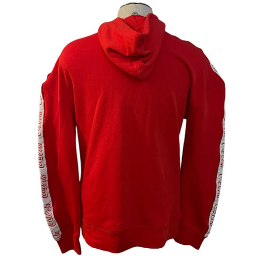 A red Coca-Cola branded pullover hoodie shown from the back on a mannequin torso, featuring white sleeve stripes with the red Coca-Cola logo printed repeatedly.