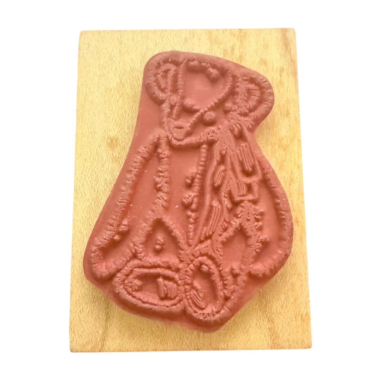 A terracotta-colored rubber stamp featuring a teddy bear design, mounted on a rectangular light wood block against a plain white background.
