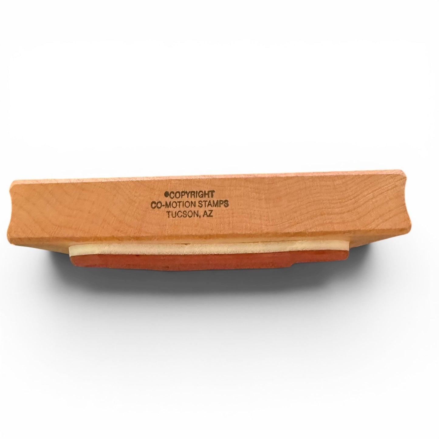 Wooden stamp with 'Co-Motion Stamps Tucson, AZ' engraving on a white background
