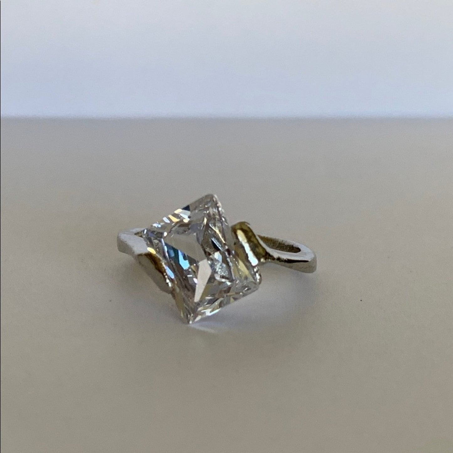 Faux Diamond ring on a beige surface with a white background