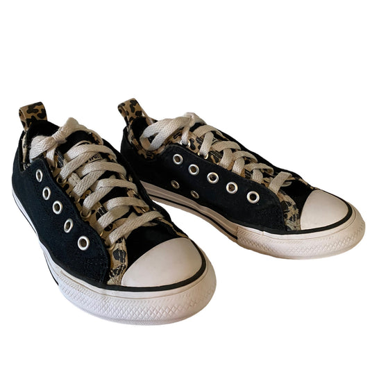 A pair of low-top canvas sneakers with black uppers, beige and black leopard-print side panels, beige laces, and white rubber toe caps and soles, shown on a plain white background.
