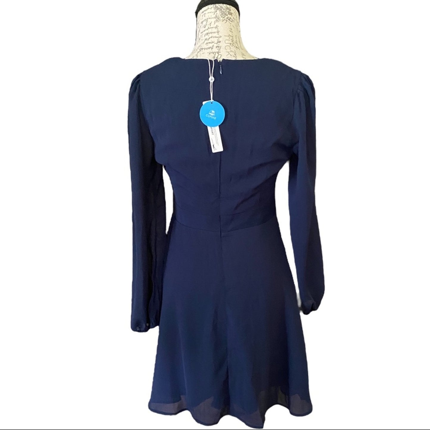 Back of Navy blue dress on a mannequin with a visible tag against a white background