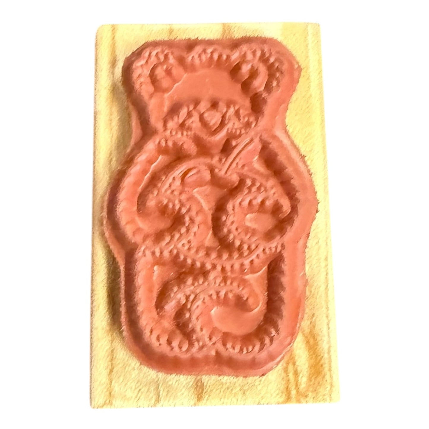 A bear-shaped stamp , mounted on a rectangular wood backing, set against a plain white background.