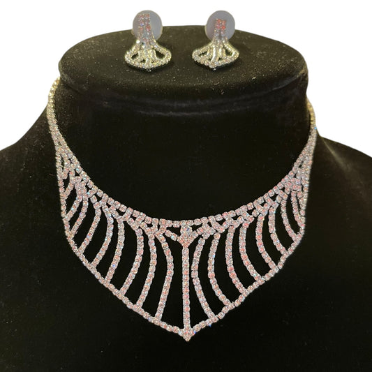 A sparkling silver-toned jewelry set featuring a wide, necklace and matching dangle earrings, displayed on a black velvet jewelry bust against a white background.