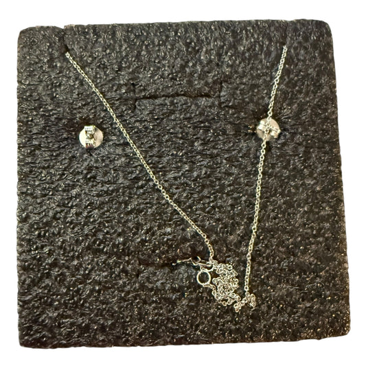 Silver back of necklace and earrings on a textured black surface
