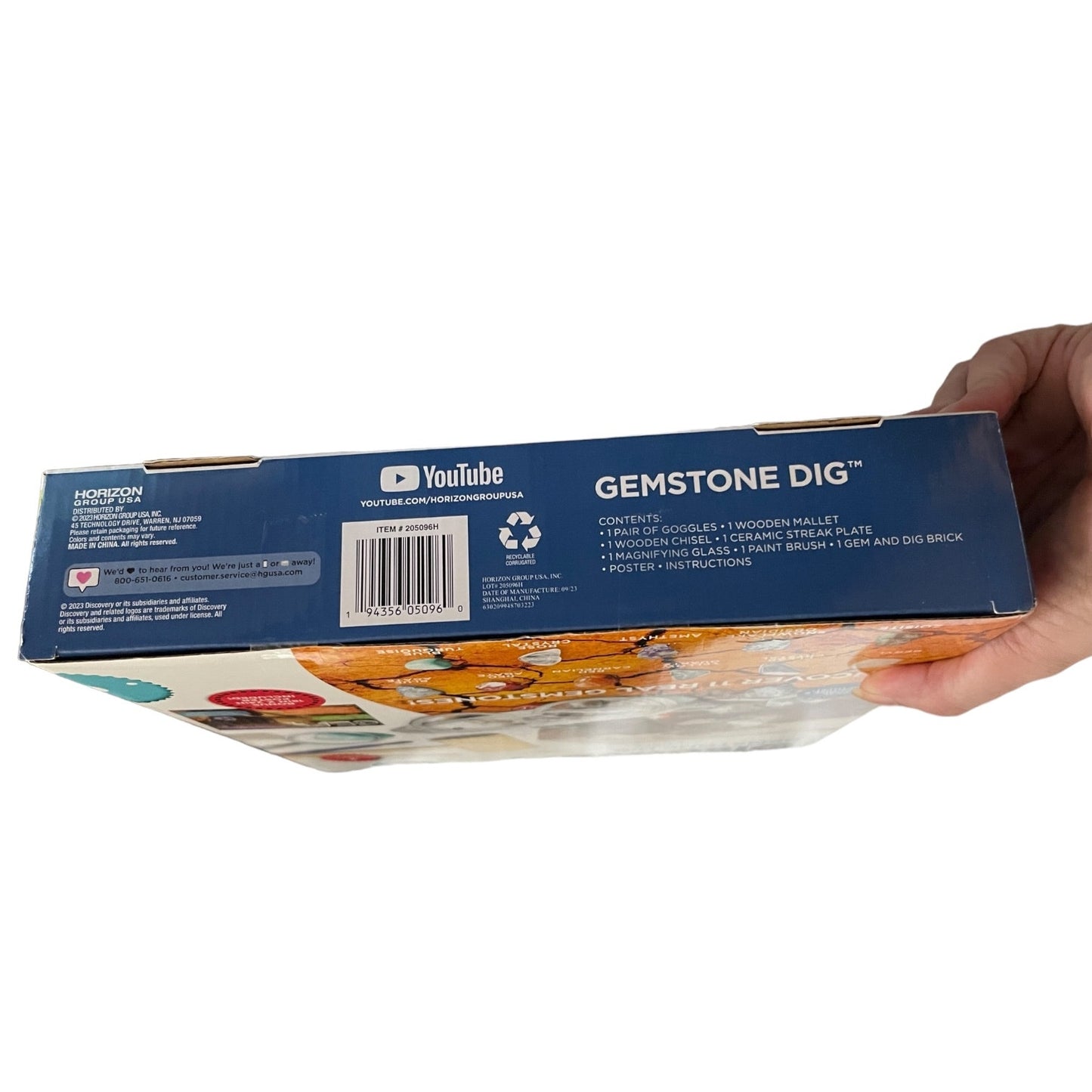 Box of 'Gemstone Dig' toy set held by a hand on a white background