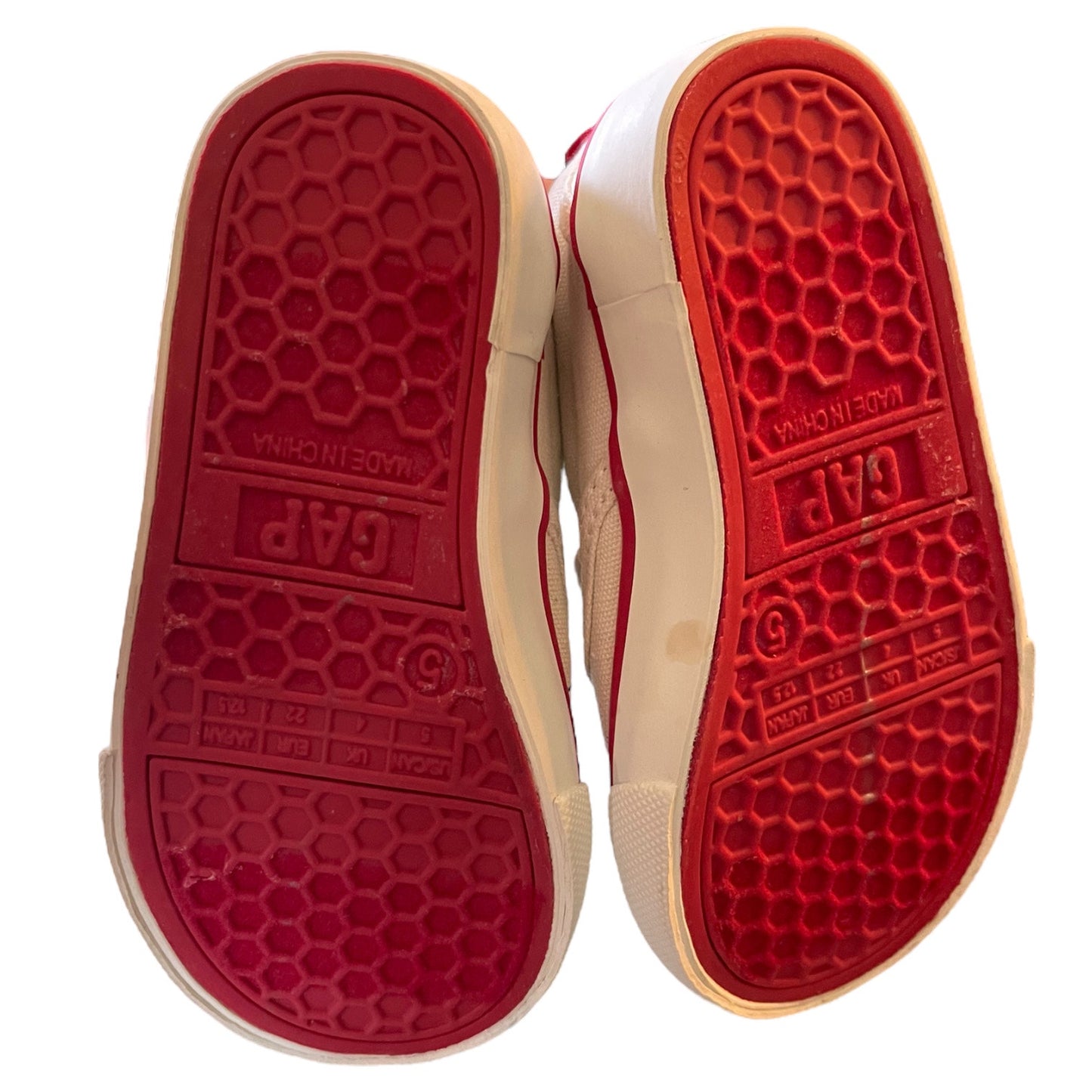 Red soles of a shoe with 'GAP' branding on a white background