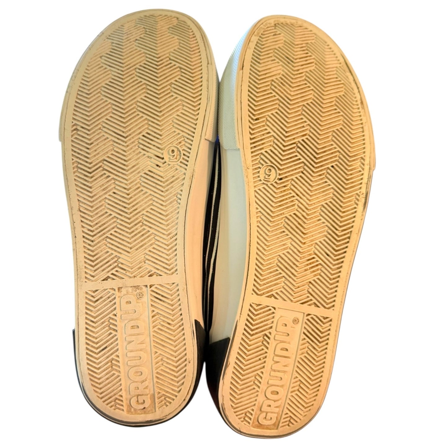 Close-up of the soles of a pair of shoes with 'Groundup' branding on a white background.