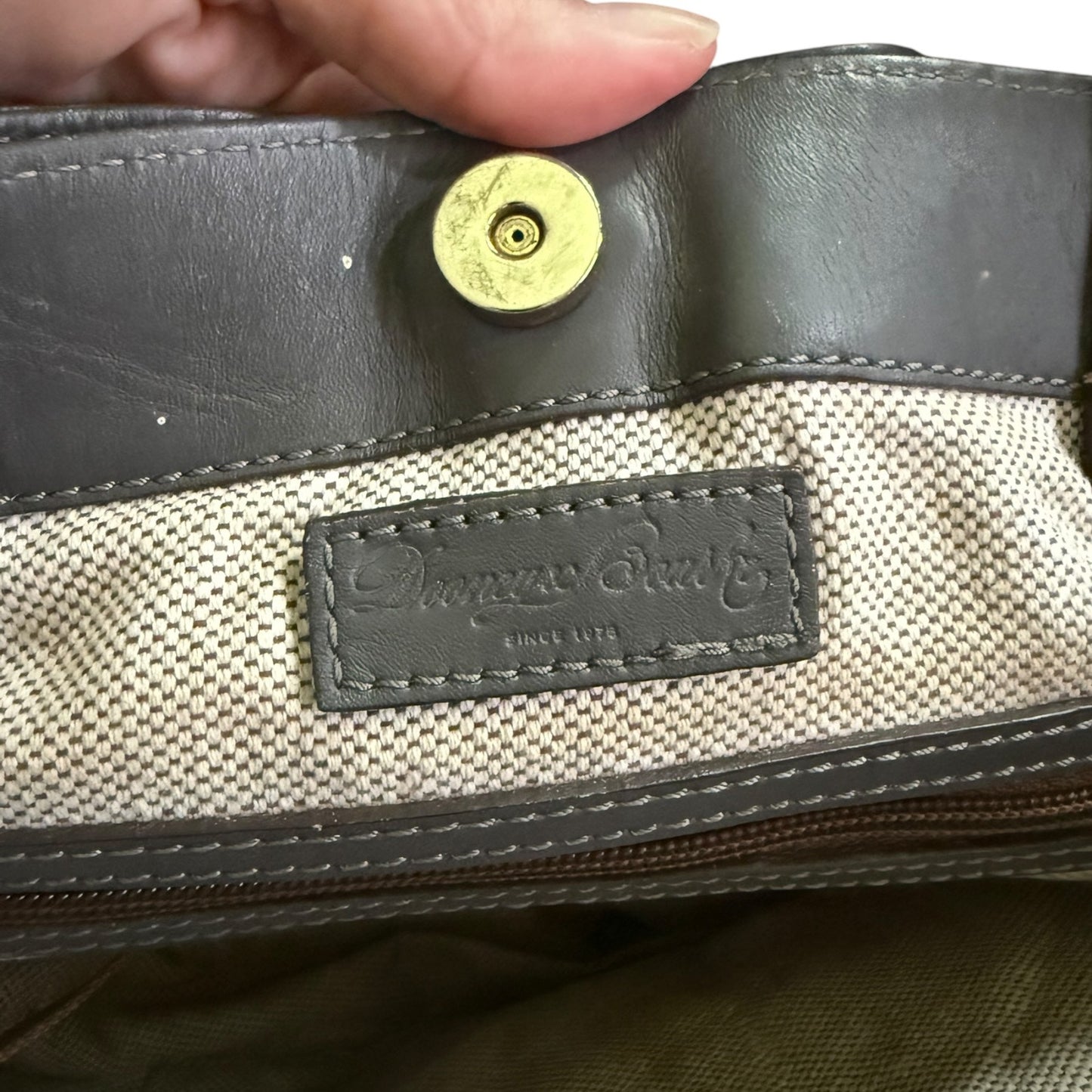 Close-up of a leather-bound bag with a visible brand label.
