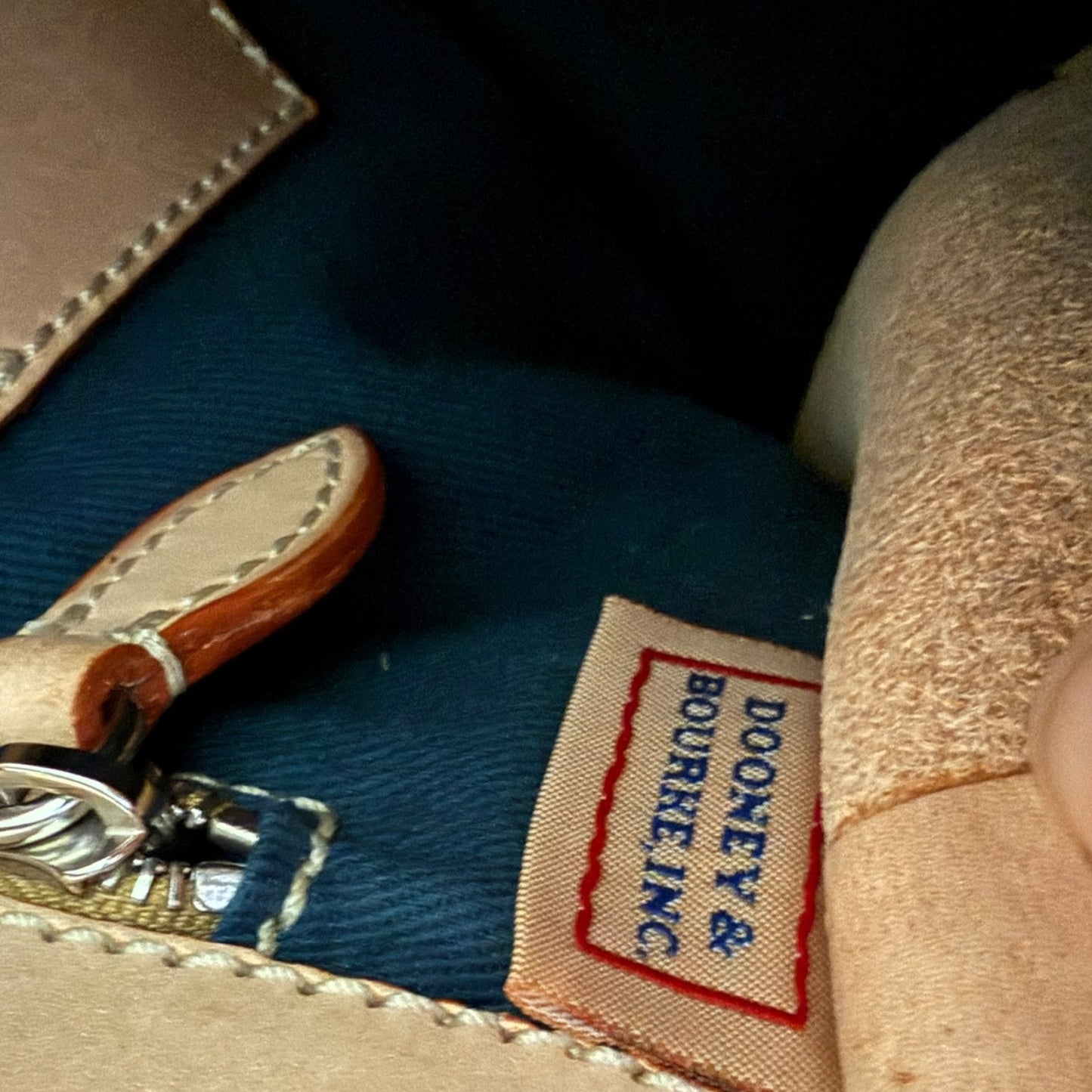 Close-up of a Dooney & Bourke label on a leather product with a blue background.