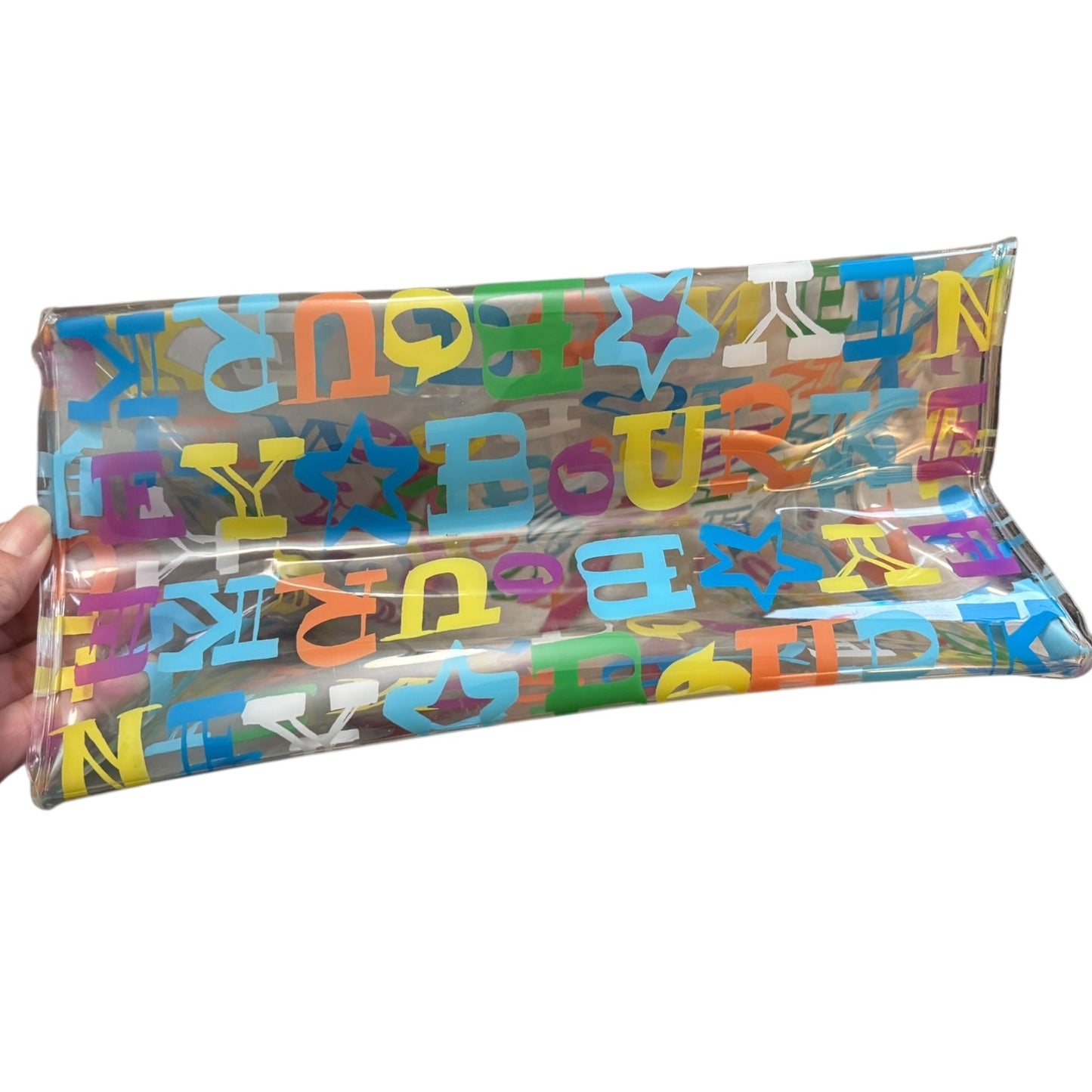 Bottom of Clear bag with colorful letters held by a hand on a white background