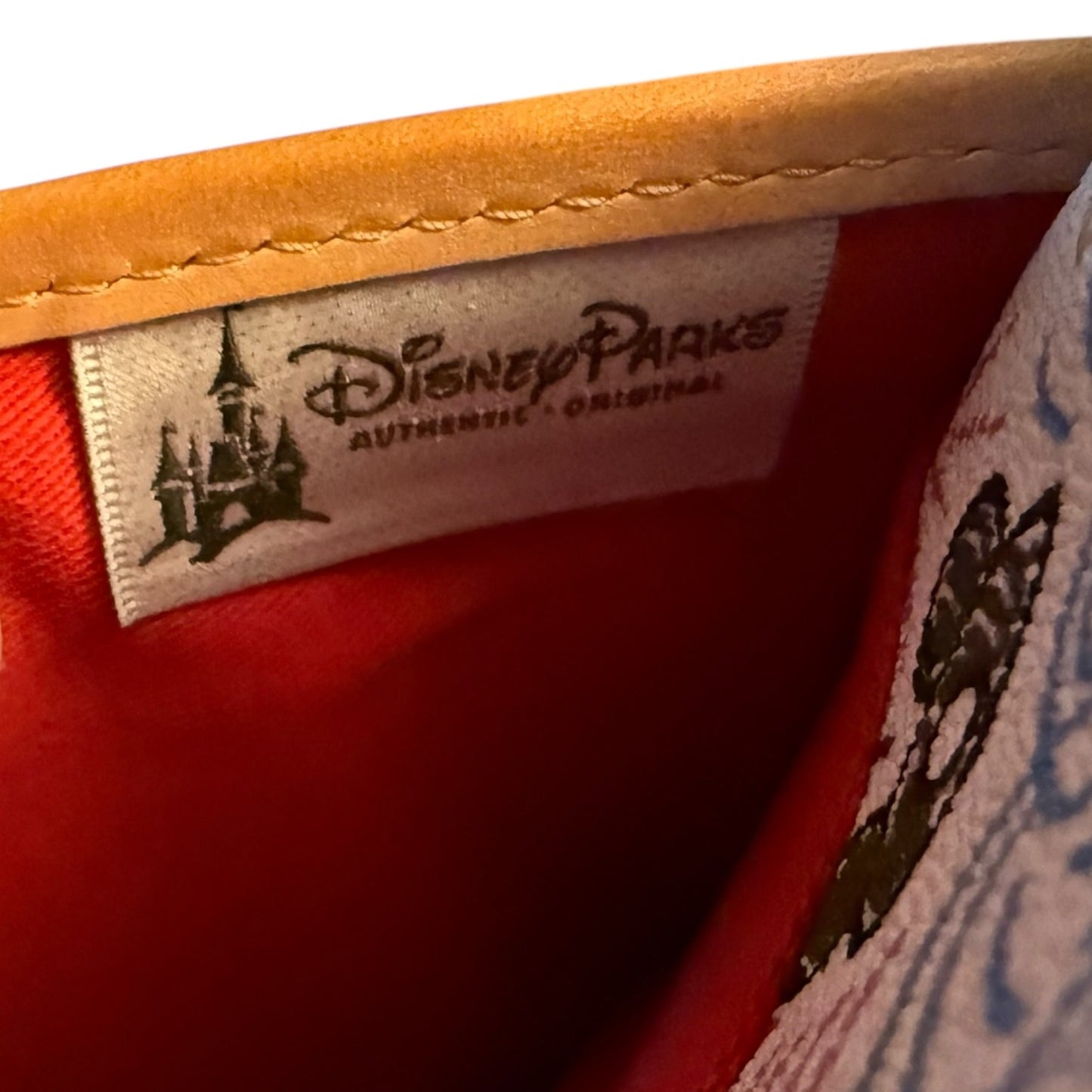 Close-up of a Disney Parks label on a product with red fabric and disney pattern.