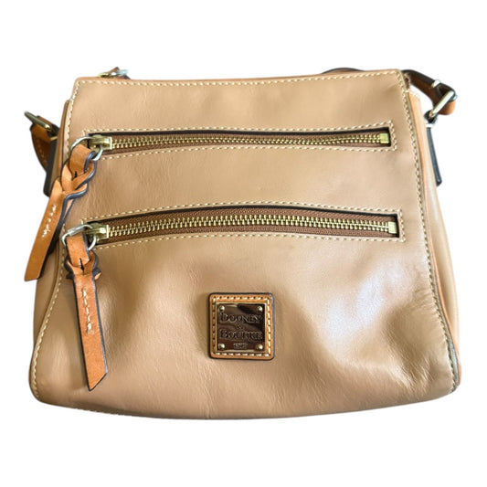 Close up of brown handbag with zippers and gold accents on a white background