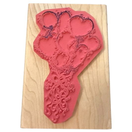 Red rubber stamp with intricate design on a wooden board