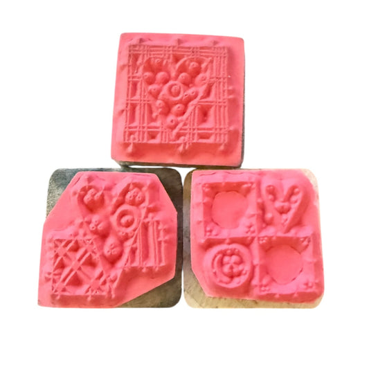 Three pink rubber stamps with heart designs on a white background